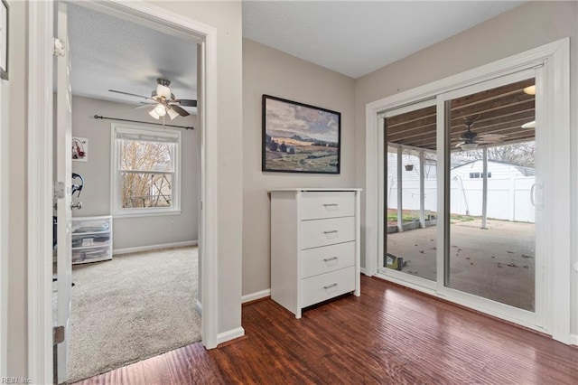 interior space featuring access to exterior, dark wood finished floors, a ceiling fan, and baseboards