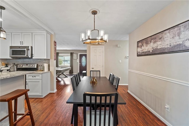 dining area featuring dark wood finished floors, a notable chandelier, and baseboards