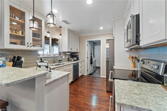 kitchen with visible vents, light stone countertops, a peninsula, stainless steel appliances, and a sink