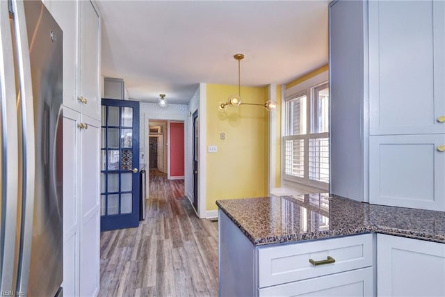 kitchen featuring dark stone countertops, white cabinetry, light wood finished floors, and freestanding refrigerator