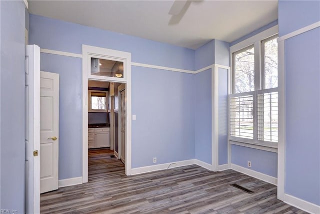 unfurnished room with a wealth of natural light, visible vents, and wood finished floors