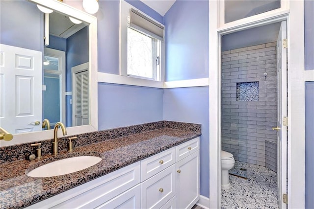 bathroom featuring vanity, toilet, and a tile shower