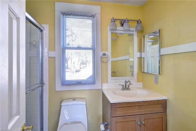 bathroom featuring toilet, vanity, and a shower with shower door