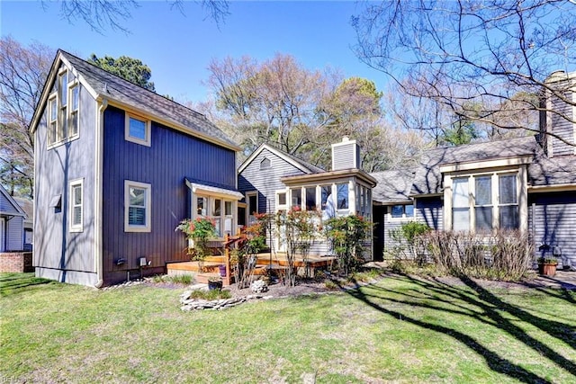 back of property featuring a shingled roof, a yard, and a chimney