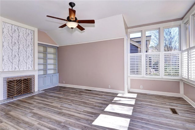 unfurnished living room with visible vents, a fireplace, baseboards, and wood finished floors