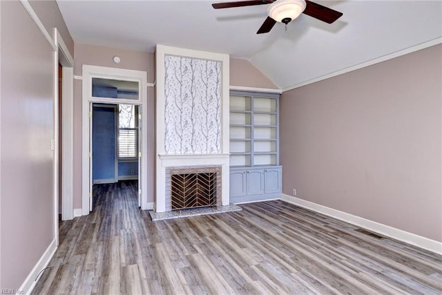 unfurnished living room with vaulted ceiling, a fireplace with raised hearth, baseboards, and wood finished floors