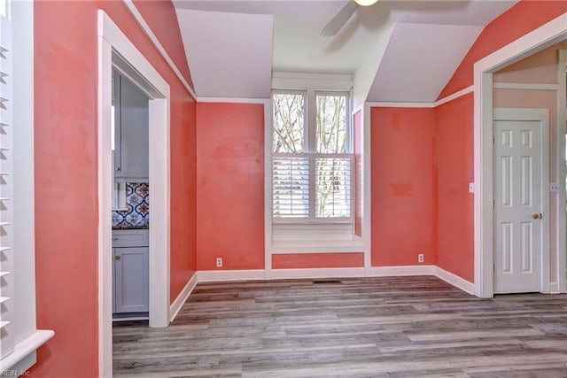 interior space featuring vaulted ceiling, ceiling fan, baseboards, and wood finished floors