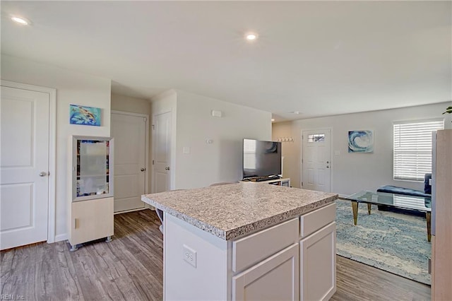 kitchen with light wood-style flooring, a kitchen island, recessed lighting, white cabinets, and light countertops