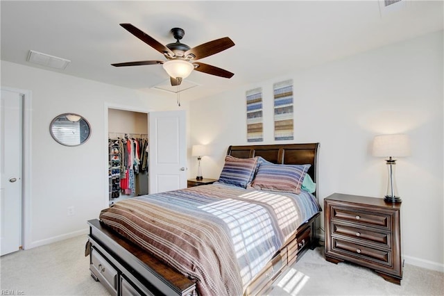 bedroom with visible vents, baseboards, a closet, a walk in closet, and light colored carpet