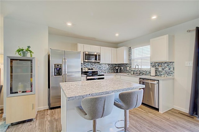 kitchen with visible vents, backsplash, a kitchen island, stainless steel appliances, and a sink