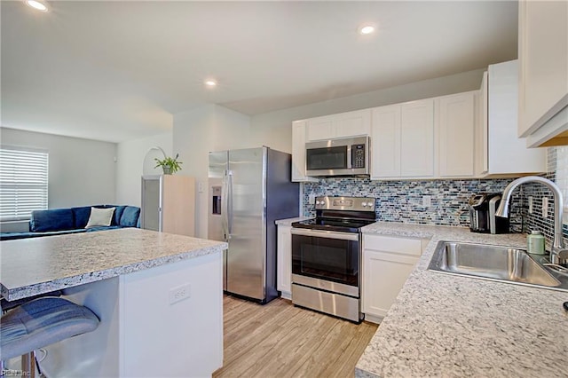 kitchen featuring appliances with stainless steel finishes, light countertops, light wood-style floors, and a sink