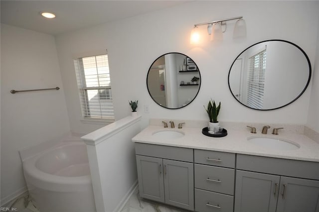 full bath featuring a garden tub, marble finish floor, and a sink