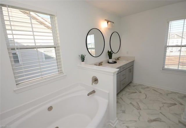 bathroom with a bath, plenty of natural light, marble finish floor, and a sink