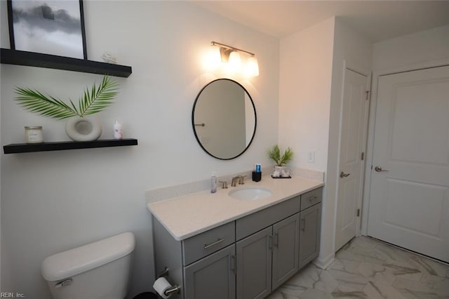 bathroom featuring toilet, marble finish floor, and vanity