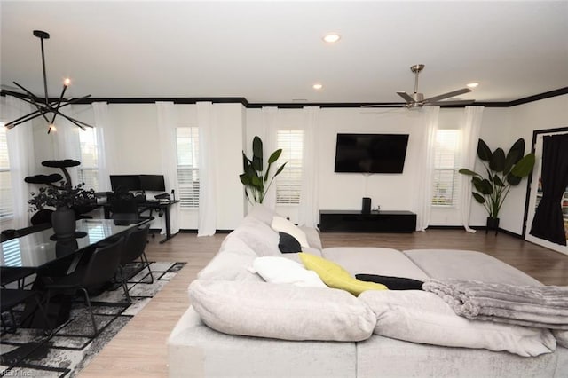 living area featuring a notable chandelier, a healthy amount of sunlight, wood finished floors, and crown molding