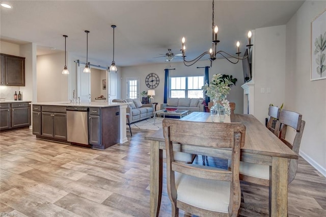 dining space featuring ceiling fan with notable chandelier, baseboards, and light wood finished floors