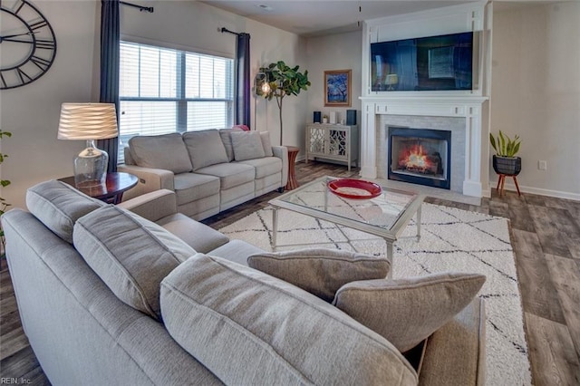 living area with a fireplace with flush hearth, baseboards, and wood finished floors