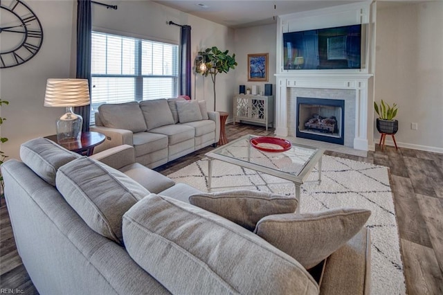 living room featuring a fireplace with flush hearth, wood finished floors, and baseboards