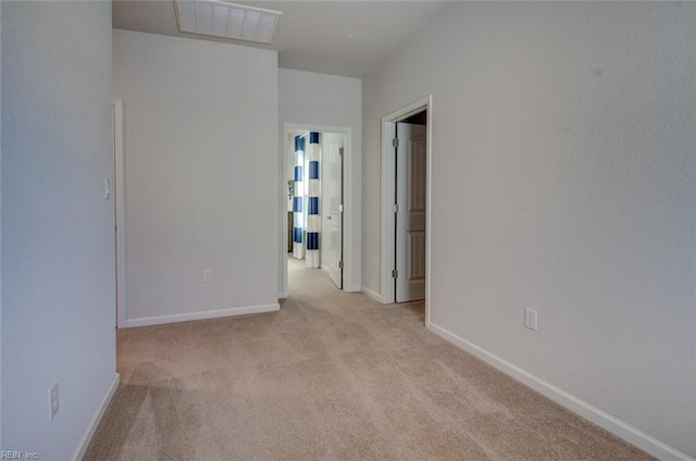 empty room featuring visible vents, light colored carpet, and baseboards