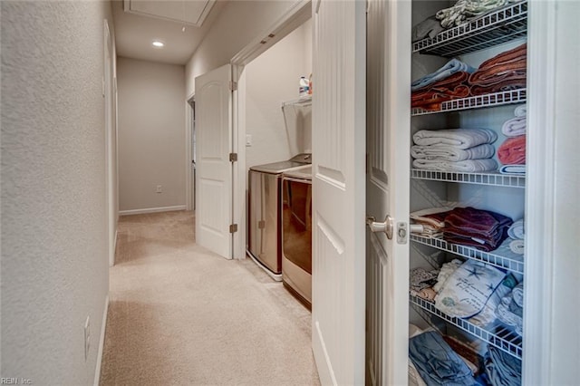 corridor featuring washing machine and clothes dryer, baseboards, attic access, carpet flooring, and a textured wall