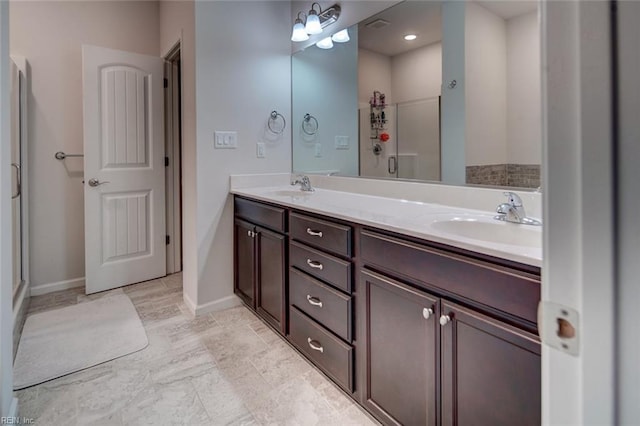 full bath featuring double vanity, a shower stall, baseboards, and a sink