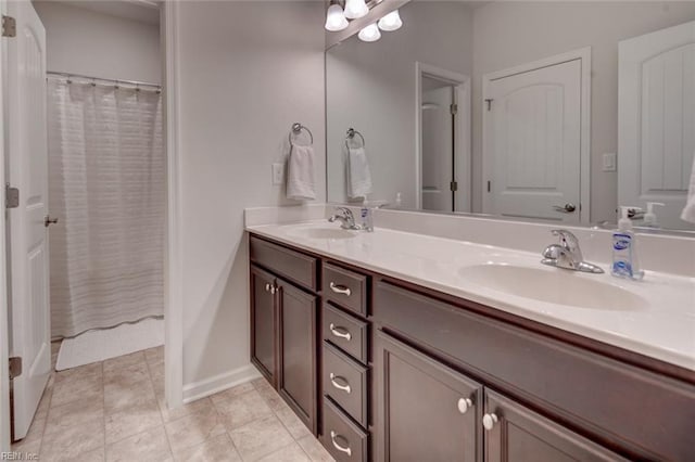 bathroom with a sink, baseboards, double vanity, and tile patterned floors