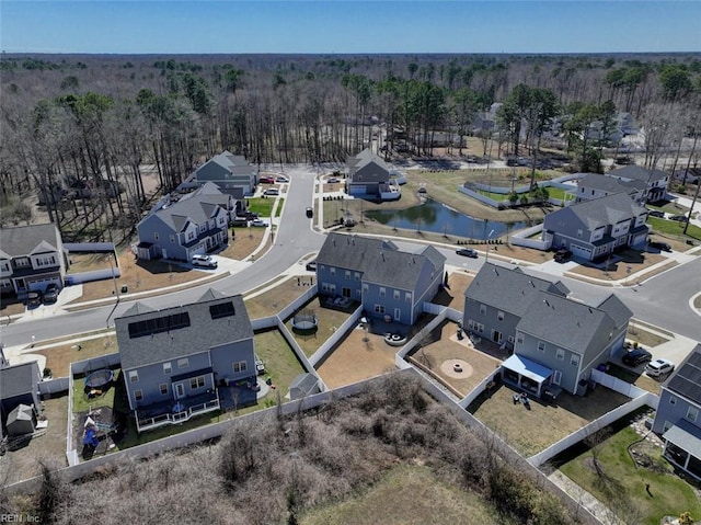 drone / aerial view featuring a residential view, a wooded view, and a water view