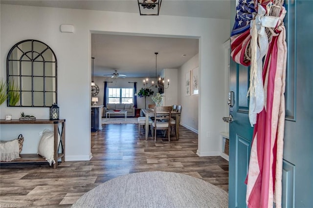 foyer entrance featuring ceiling fan with notable chandelier, wood finished floors, and baseboards