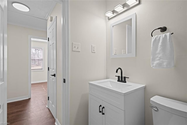 bathroom featuring vanity, toilet, wood finished floors, and baseboards