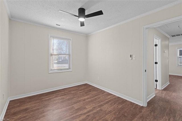 unfurnished room with visible vents, dark wood-type flooring, attic access, and ornamental molding