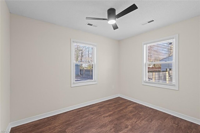 spare room featuring dark wood finished floors, visible vents, and baseboards