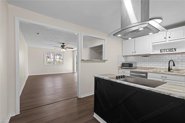 kitchen featuring backsplash, appliances with stainless steel finishes, island range hood, white cabinets, and a sink