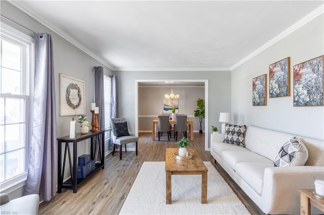 living room featuring an inviting chandelier, light wood-style flooring, baseboards, and ornamental molding