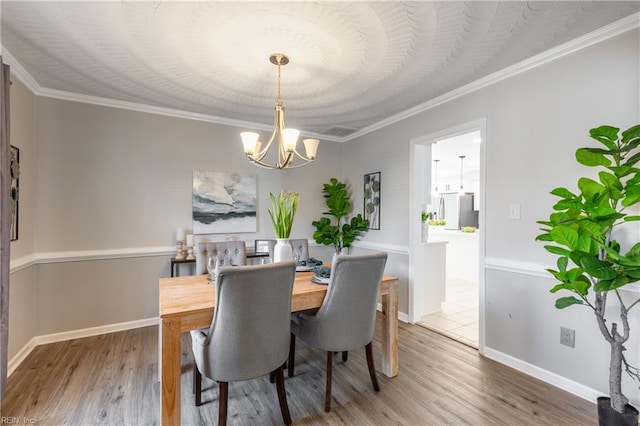 dining space with ornamental molding, baseboards, an inviting chandelier, and wood finished floors