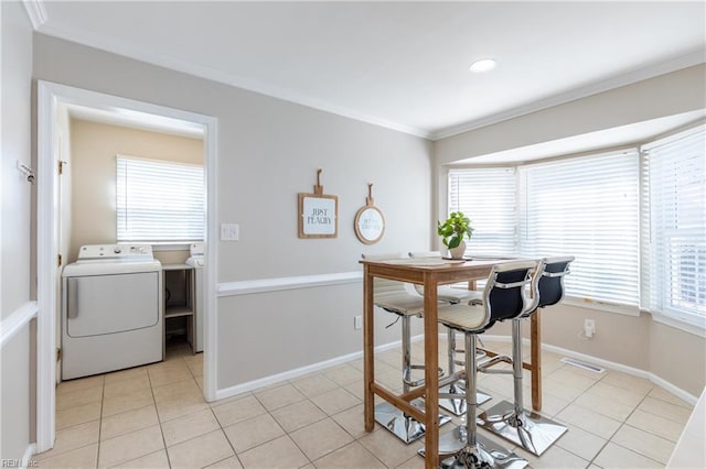 dining area with visible vents, baseboards, light tile patterned flooring, ornamental molding, and washer and clothes dryer