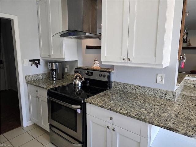 kitchen with electric range, stone counters, white cabinetry, and wall chimney exhaust hood