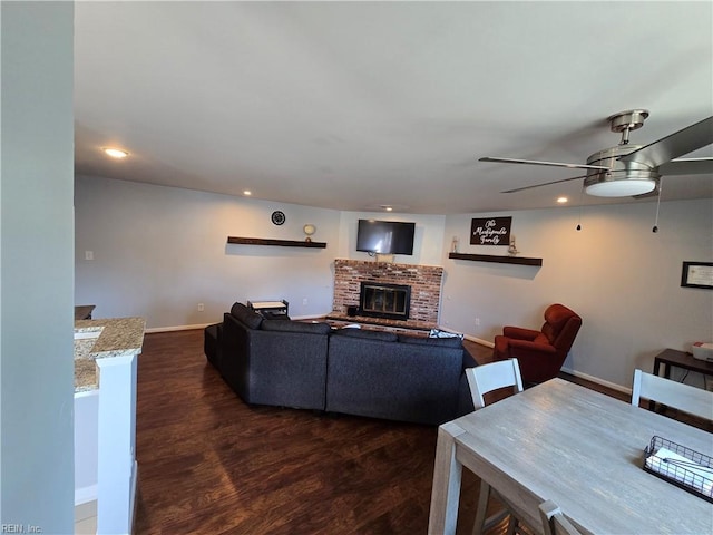 living room with recessed lighting, baseboards, dark wood-type flooring, and a brick fireplace