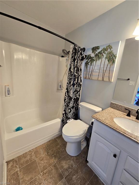 bathroom featuring toilet, shower / bath combo with shower curtain, and vanity