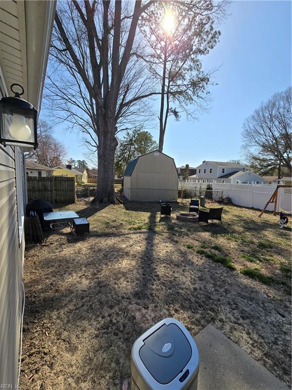 view of yard featuring a storage unit, an outdoor structure, and fence