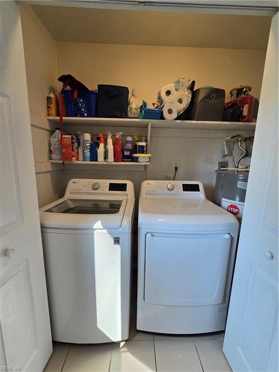 washroom with light tile patterned floors, electric water heater, independent washer and dryer, and laundry area