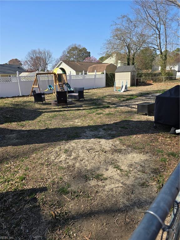 view of yard with an outbuilding, a playground, a fenced backyard, and a shed