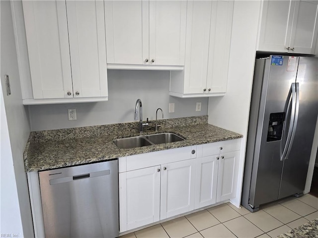 kitchen featuring white cabinets, stainless steel appliances, dark stone counters, and a sink