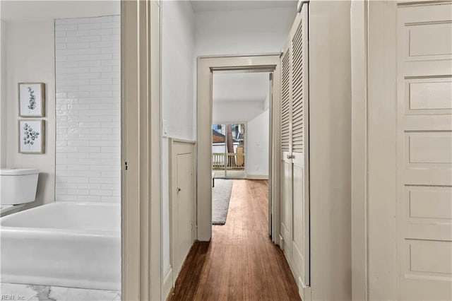 hall with dark wood-type flooring and a wainscoted wall