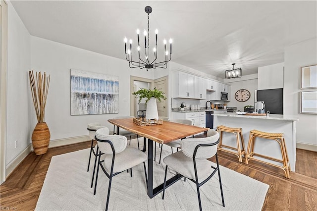 dining area with a chandelier, baseboards, and wood finished floors