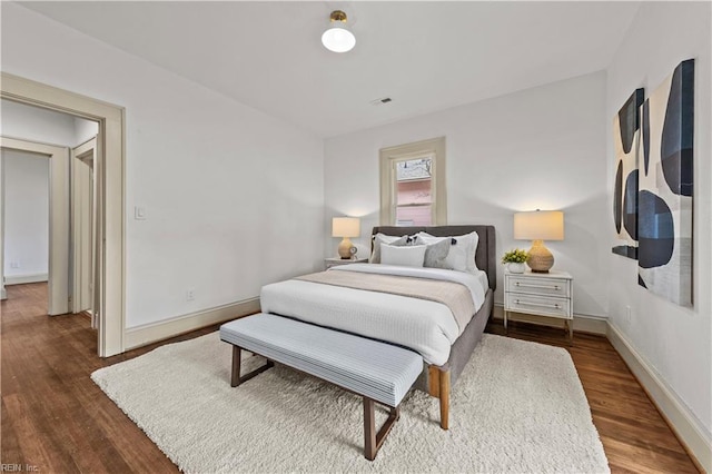 bedroom with visible vents, baseboards, and wood finished floors