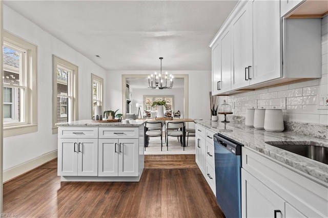 kitchen with a wealth of natural light, dark wood-type flooring, dishwasher, and an inviting chandelier