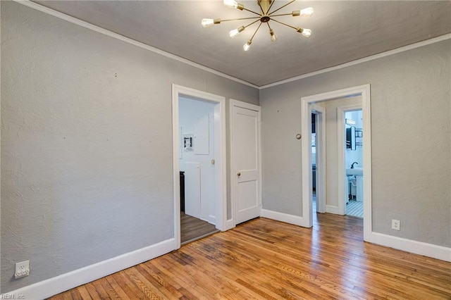 spare room featuring a notable chandelier, crown molding, a textured wall, and hardwood / wood-style floors