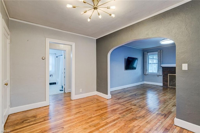 unfurnished room with arched walkways, wood finished floors, and ornamental molding