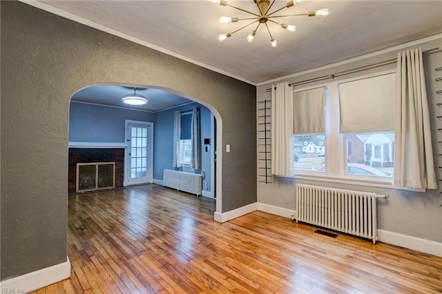 unfurnished living room with radiator heating unit, a textured wall, and ornamental molding