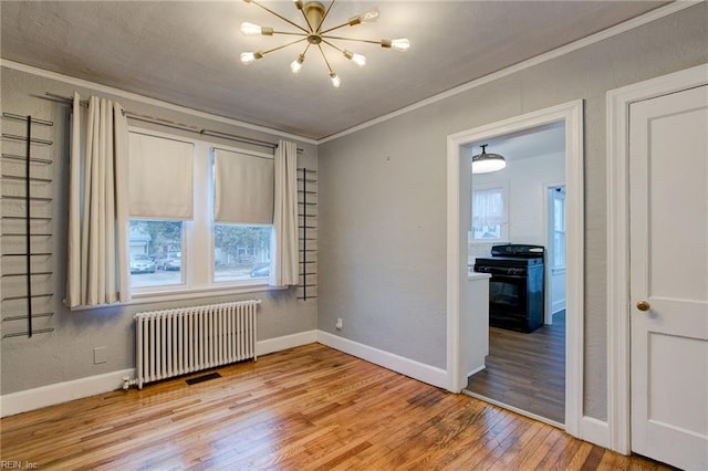 unfurnished room with plenty of natural light, crown molding, radiator heating unit, and hardwood / wood-style floors